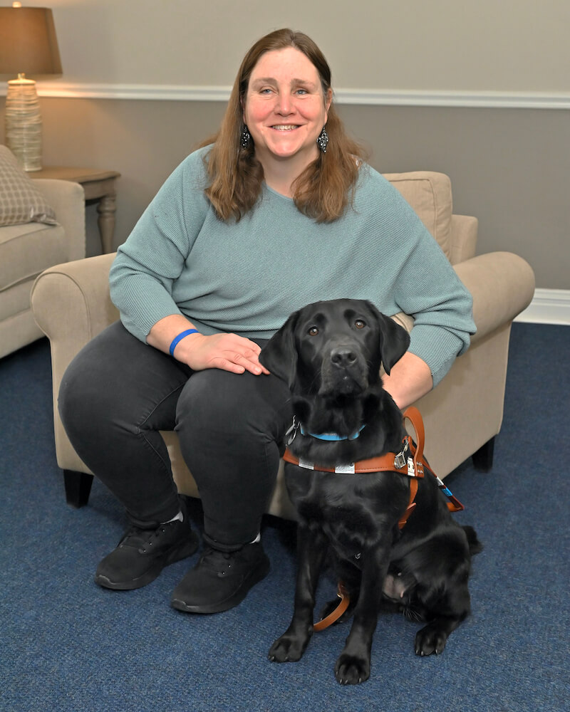 Donna and black Lab guide dog Toby sit for team photo