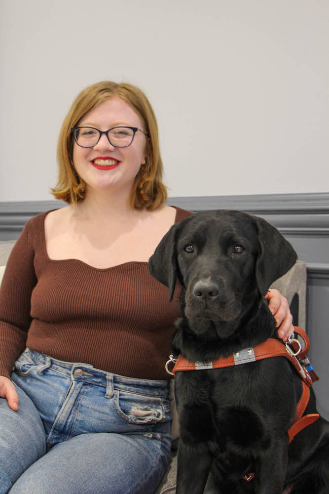 Emma and black Lab guide dog Holly sit for team portrait