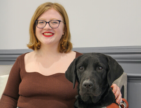 Emma and black Lab guide dog Holly sit for team portrait