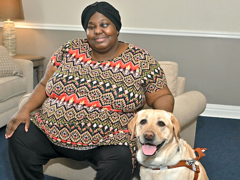 Jaydene in a beige chair, and Nita sit for their team portrait
