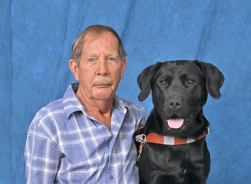 John and black Lab Dora sit for grad team portrait