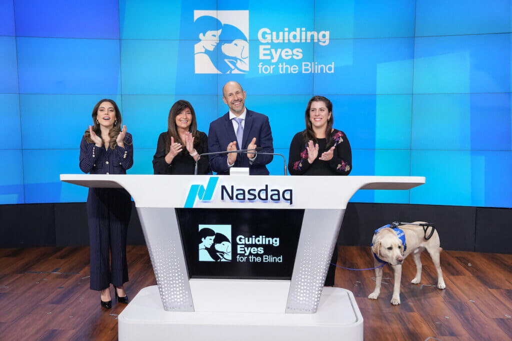 Janine, Thomas and Danielle clapping at Nasdaq podium with Blaze nearby