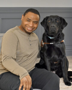 Ronnie and black Lab guide dog Flower sit head to head for the team portrait