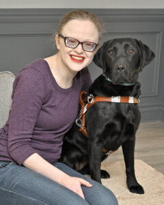 Tiffani and black lab guide dog Maggie sit with heads close for team portrait