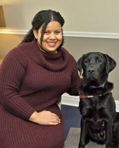 Victoria sits with black Lab guide dog at her shoulder, for their team portrait