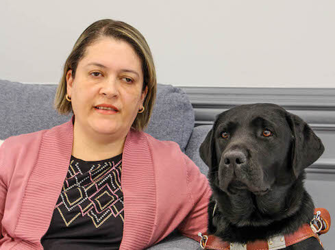 Vivian sits next to black lab guide dog Emmylou for team portrait
