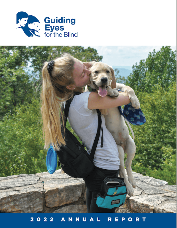 Annual Report 2022 young woman with long blonde ponytail and backpack at stonewall lookout point hugs young outstretched yellow puppy