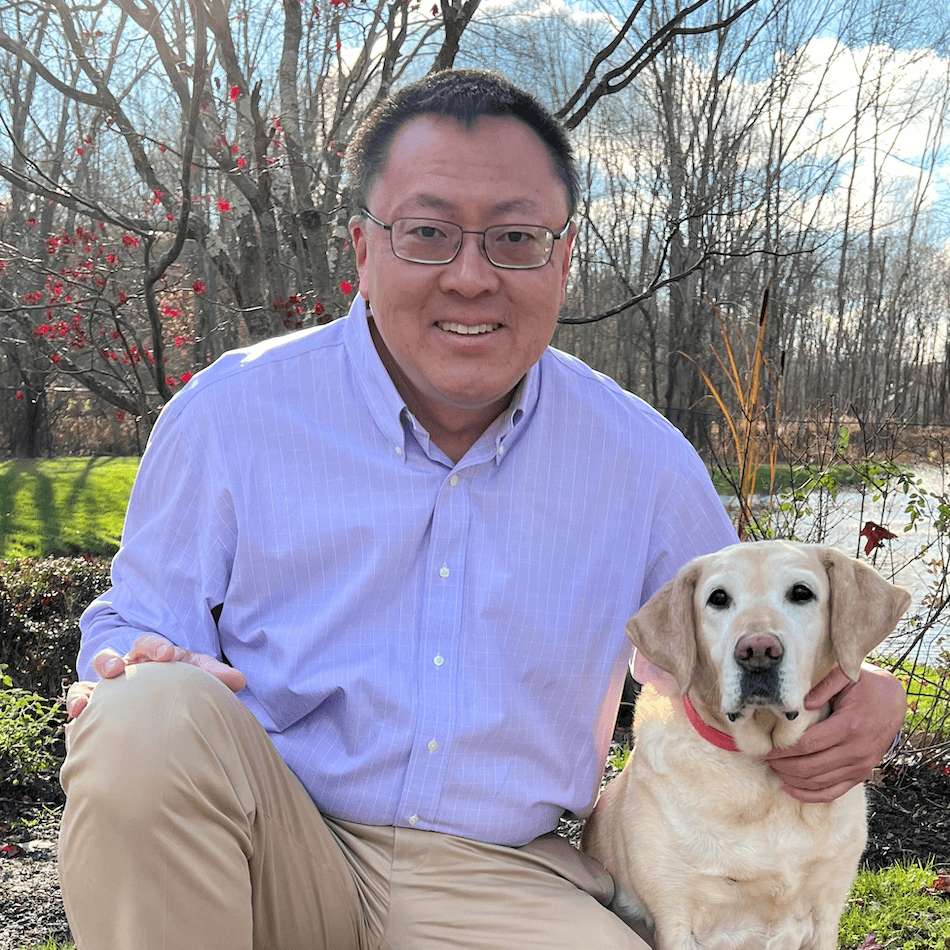 Bill Ma Head of Technology Operations on one knee next to adopted retired guide Peace