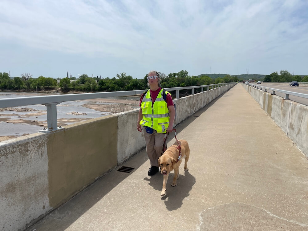 Darla and Biscotti walk down a long closed cement path adjacent to the highway