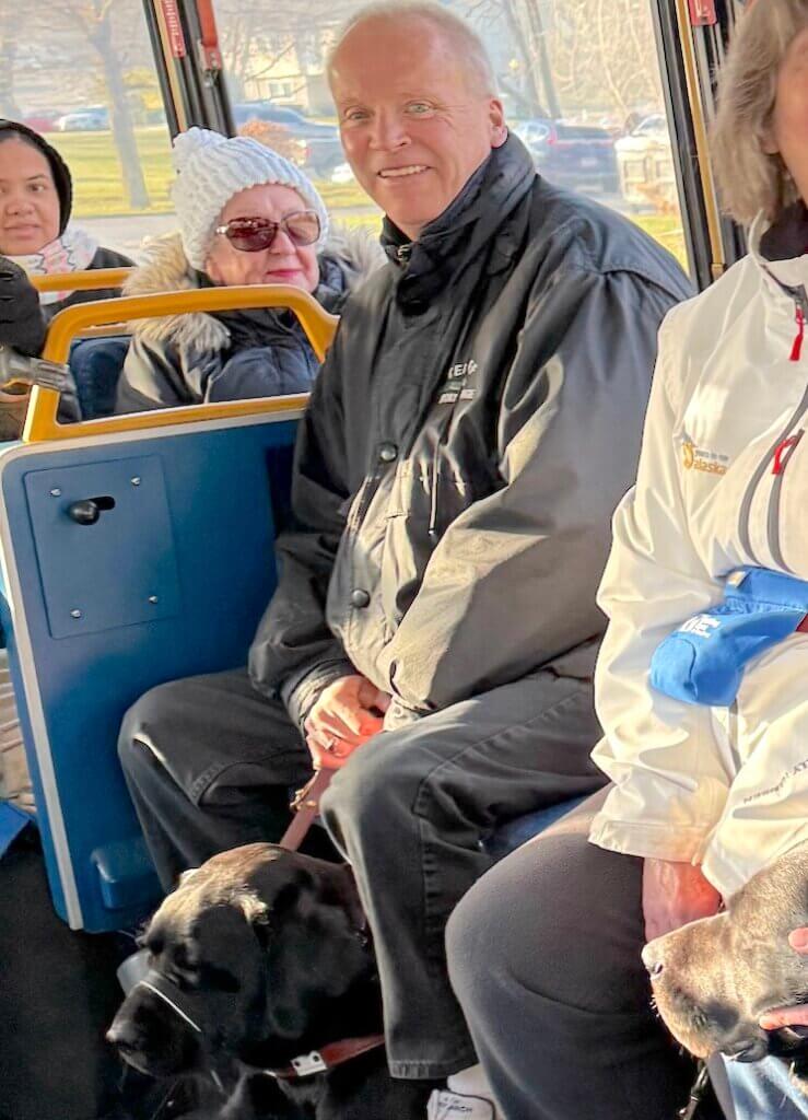Greg sits with guide dog Vern on public transit