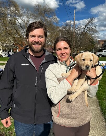 A young couple happily hold yellow puppy Ingram as first time puppy raisers