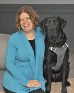 Erin and black lab guide dog Neptune sit for team portrait