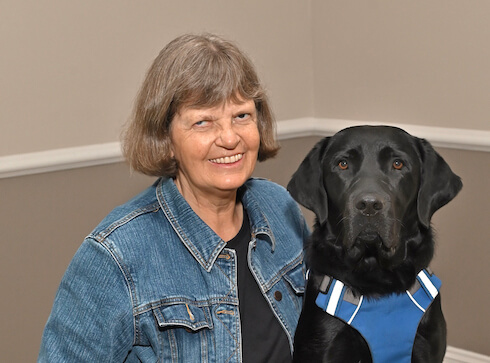Megan and black Lab guide Fulton sit side by side for their team portrait