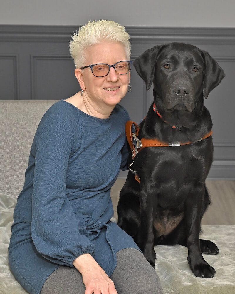 Pamela leans closeto black Lab guide dog Mary for their team portrait
