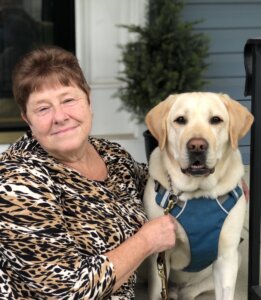 Tara and yellow Lab guide dog Blanco sit on a front step for team portrait