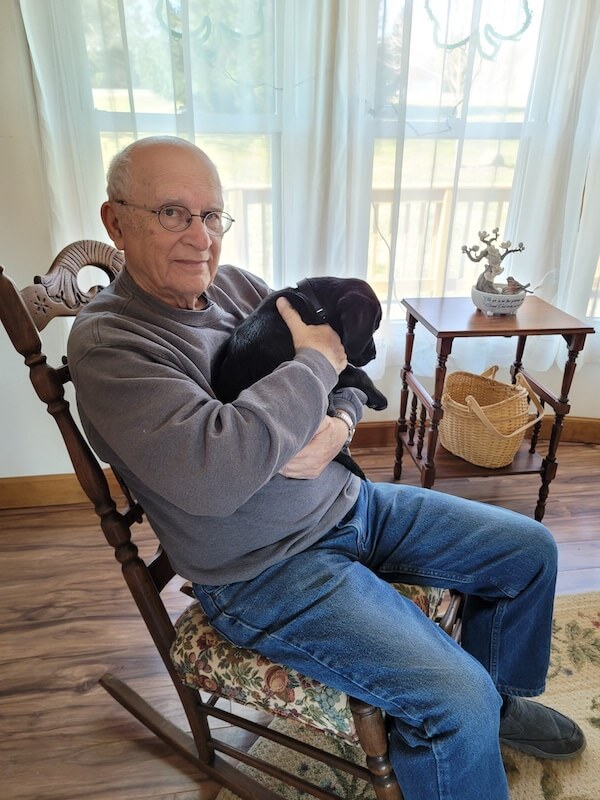 puppy Douglas snuggles in the rocker with raiser Terry