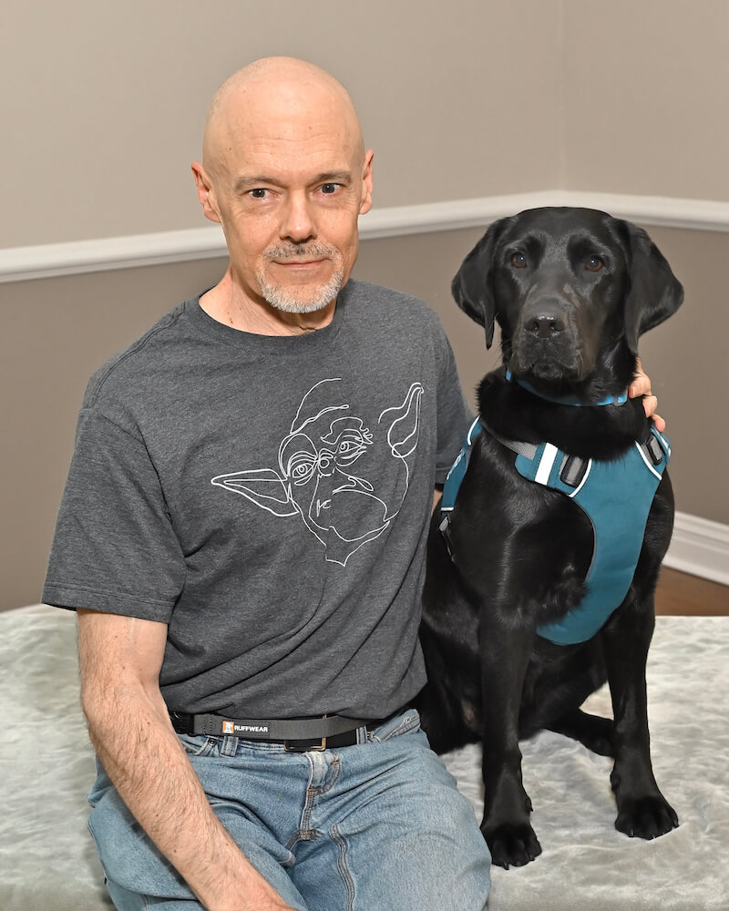 Tony and black Lab guide Imari sit for their graduate portrait