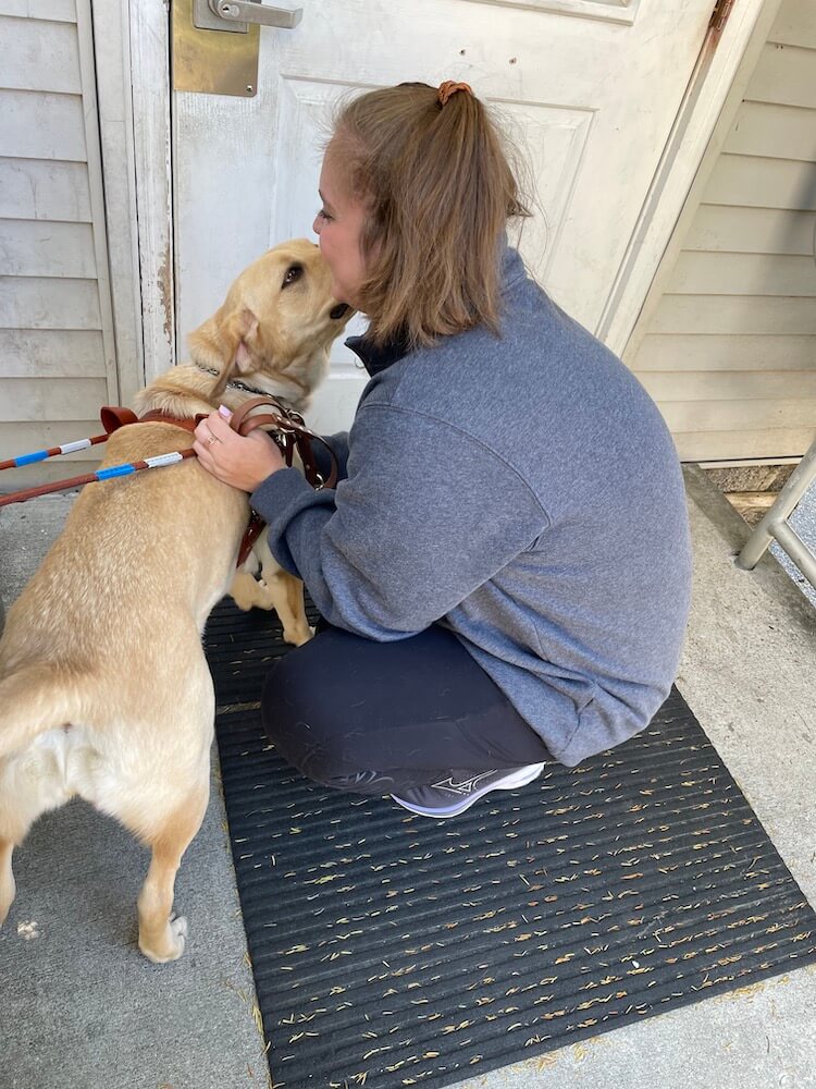 Ashley squats down to get kisses from guide Hawaii after a training run