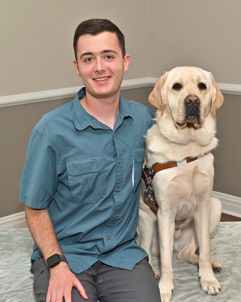 Jack and yellow Lab guide Laredo sit for they graduate portrait