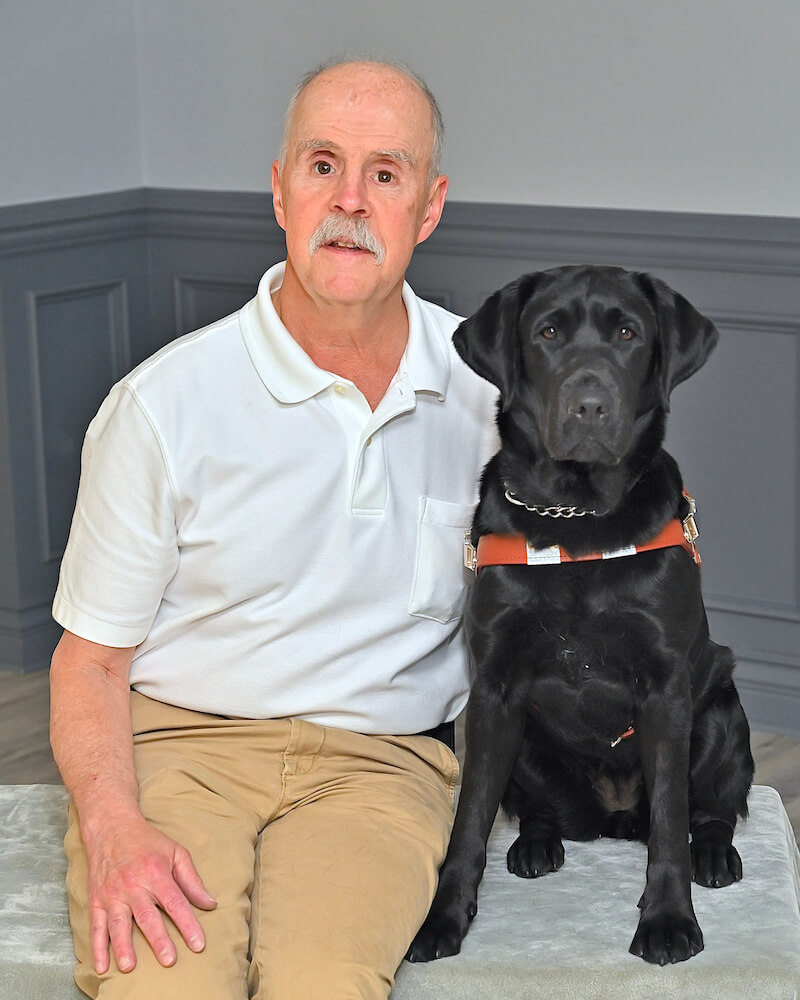 Paul and black lab guide Wilder sit for team portrait