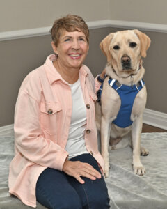 Sandra and yellow Lab guide Orla sit together for team portrait