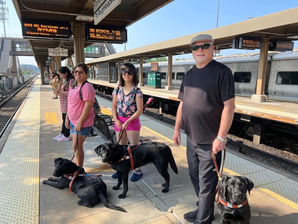 Jen, Phuong and James with guide dogs on train platform