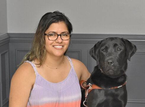 Jen and black lab guide dog Olive sit for team portrait