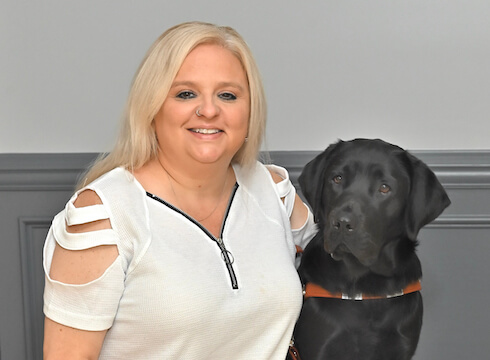 Mandy and black lab guide dog Reina sit for team portrait
