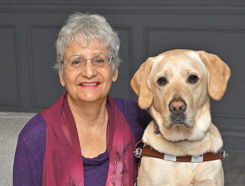 Larriece sits with yellow lab guide dog Oliver for team portrait