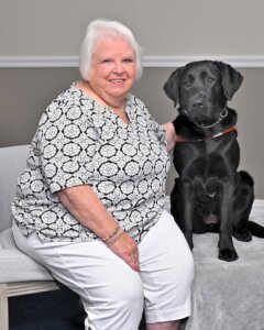 Catherine sits next to black Lab guide dog Meg for team portrait