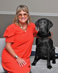 DeAnna sits next to black Lab guide dog Whimsey for team portrait