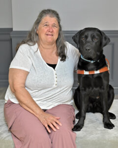 Irene sits next to black Lab guide dog Tex for team portrait