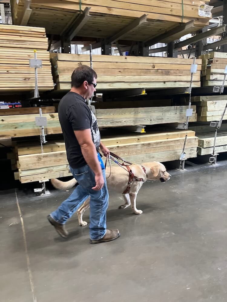 Travis and guide Francisco walk quickly past lumber racks in big box store