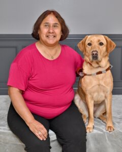 Catalina sits with yellow Lab guide dog Zephyr for their graduate portrait