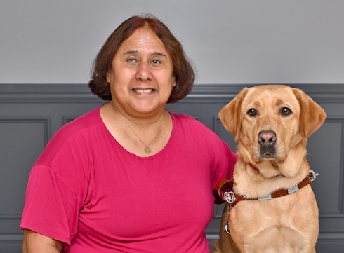 Catalina sits with yellow Lab guide dog Zephyr for their graduate portrait