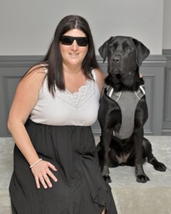 Kayla and black lab guide dog Cayenne sit head to head for team portrait