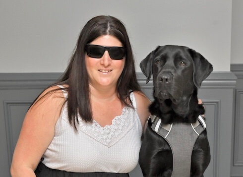 Kayla and black lab guide dog Cayenne sit head to head for team portrait