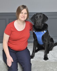 Kira leans towards black Lab guide Kona as they sit side by side for team portrait