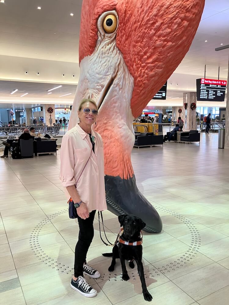 Deni and Hildy stand in front of a giant Flamingo head at Tampa airport
