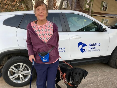 Marcie and guide Kobe stand by Guiding Eyes vehicle