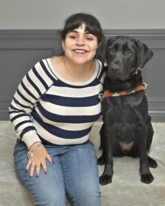 Mari leans into black Lab guide dog Betty for their team portrait