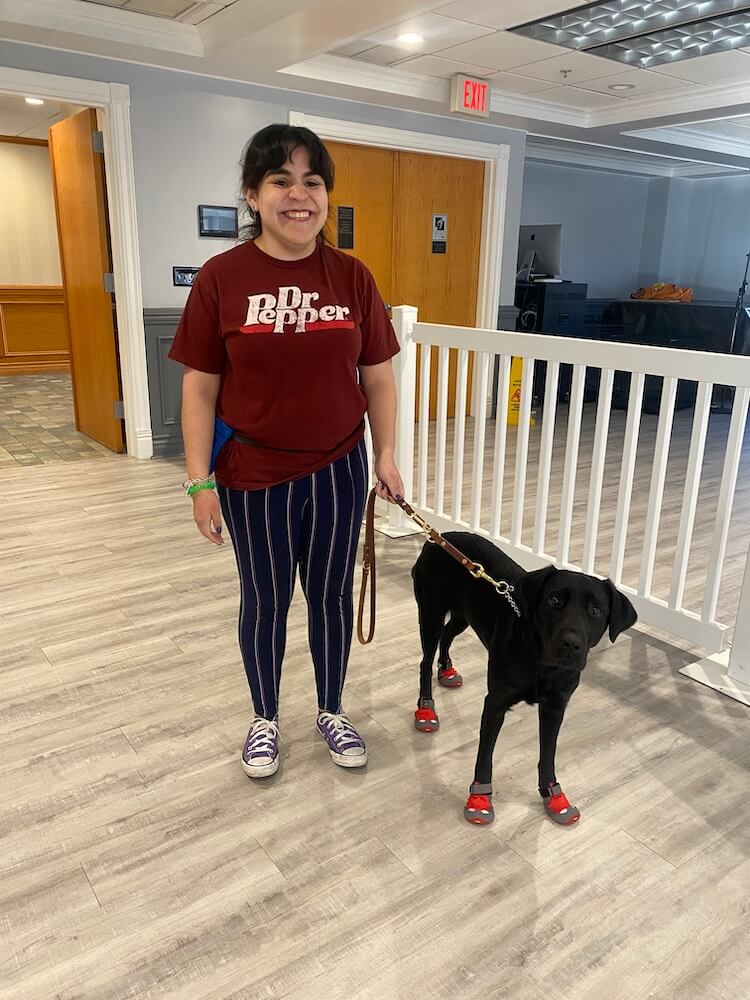Mari happily stands in Alumni Hall with guide Betty on a leash