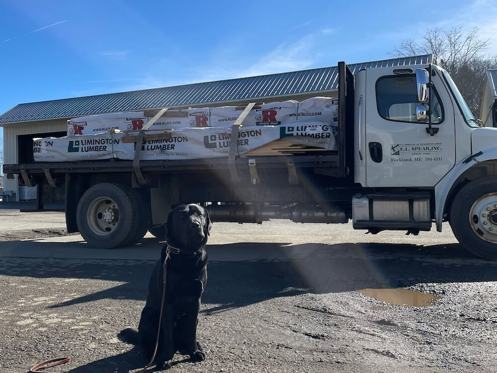 Kobe, pup on program, sits near Spear Lumber truck (raiser's)