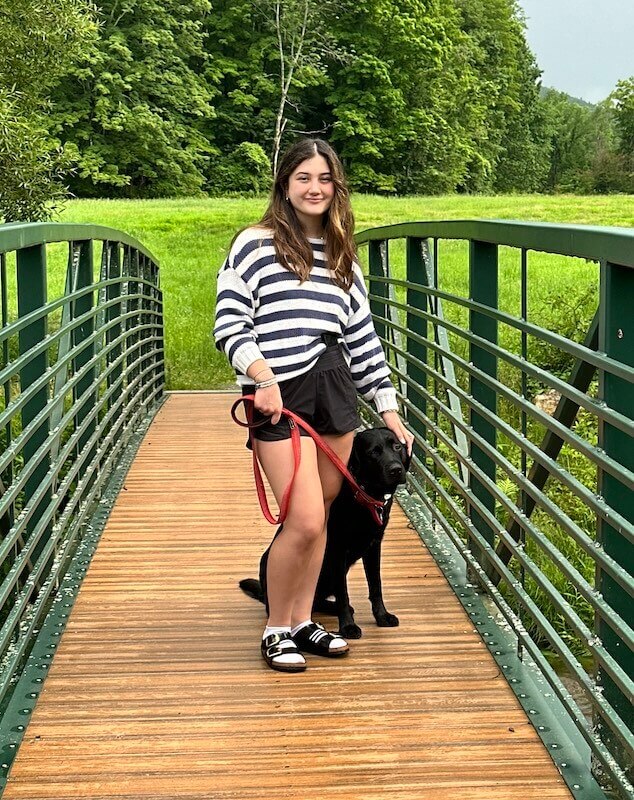 Foster Catherine with stud dog Ralphie on a green metal bridge with lawn and trees beyond