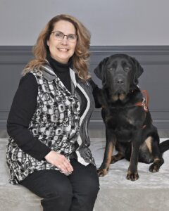 Tamisue sits with black Lab guide dog Vidal for their team portrait