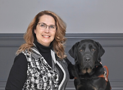 Tamisue sits with black & tan Lab guide dog Vidal for their team portrait