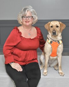 Cindy Lou is next to yellow Lab guide dog Crystal as they sit for their team portrait