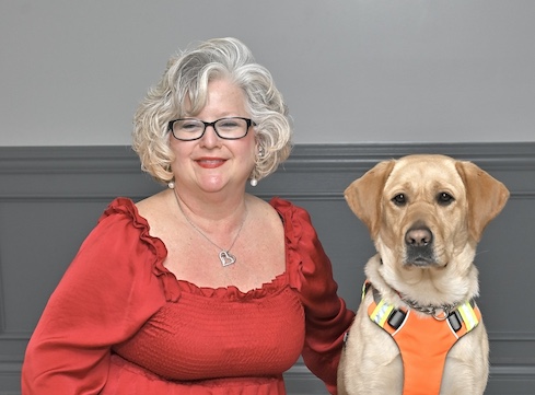 Cindy Lou is next to yellow Lab guide dog Crystal as they sit for their team portrait