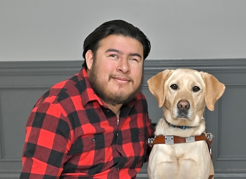 Fernando is next to yellow Lab guide dog Millie as they sit for their team portrait