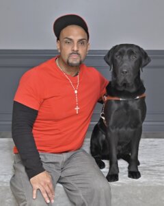 Hugo sits with black Lab guide dog Idaho for their team portrait